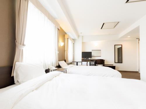 a hotel room with two beds and a window at Tabist ASAHIKAWA STATION HOTEL in Asahikawa