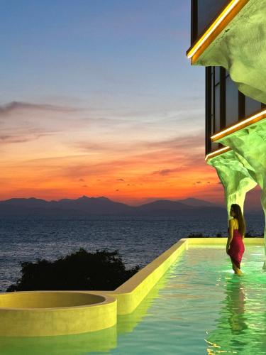 a woman standing in a infinity pool with a view of the ocean at 阿卡那拉橘子海亲子民宿 in Dapeng