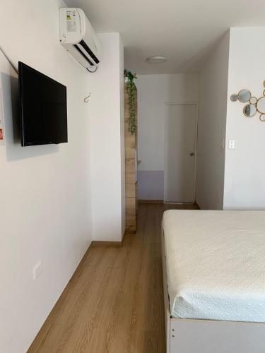 a bedroom with a bed and a flat screen tv on the wall at Los Soles Suite Mall del Sol Guayaquil Airport in Guayaquil