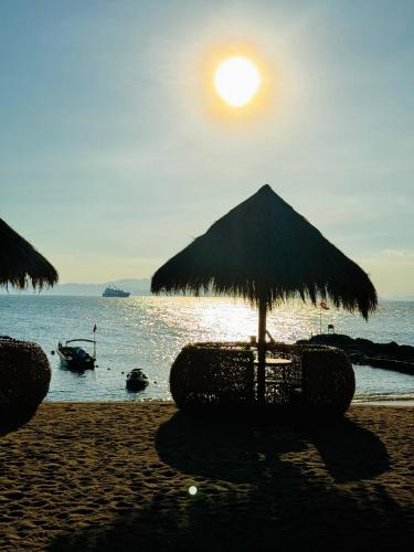 a beach with a straw umbrella and the ocean at 阿卡那拉橘子海亲子民宿 in Dapeng