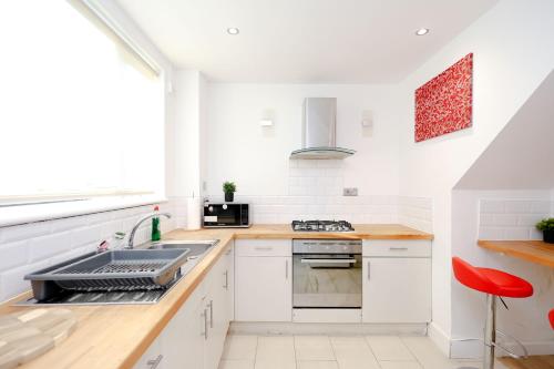 a kitchen with white cabinets and a sink at Hope Deluxe King Bedroom Manchester in Middleton