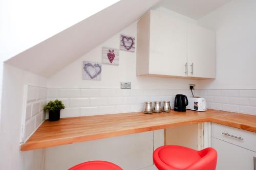 a kitchen with white cabinets and a red chair at Hope Deluxe King Bedroom Manchester in Middleton