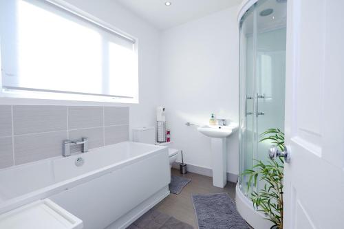 a white bathroom with a tub and a sink at Hope Deluxe King Bedroom Manchester in Middleton