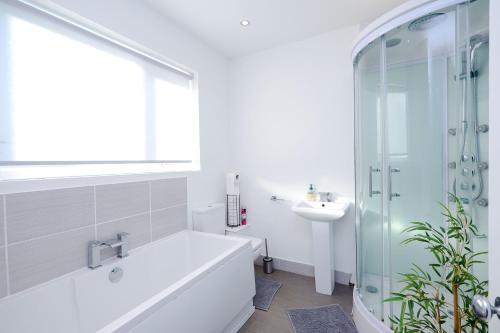 a bathroom with a tub and a glass shower at Hope Deluxe King Bedroom Manchester in Middleton