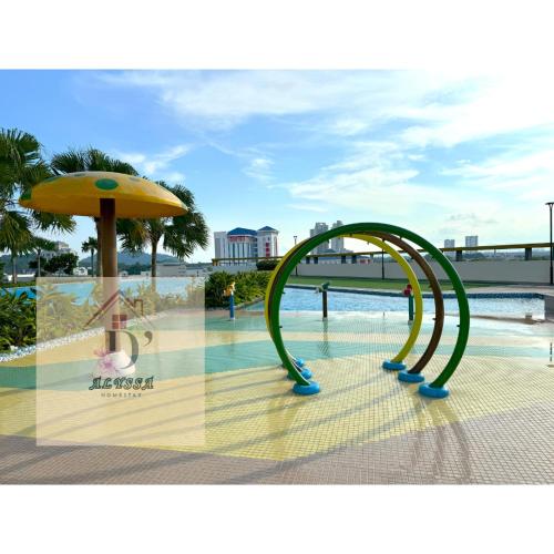 a slide in front of a pool with an umbrella at D' Alyssa Homestay Perda in Bukit Mertajam