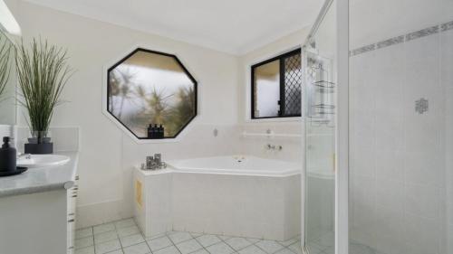 a white bathroom with a sink and a shower at Serenity Shores in Sandstone Point