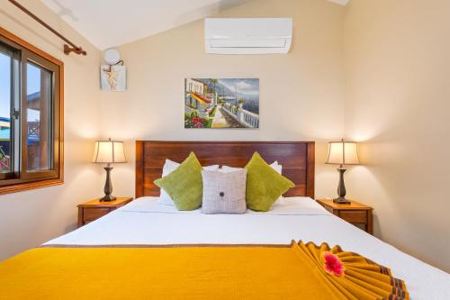 a bedroom with a bed with yellow sheets and green pillows at Coconut Row Boutique Hotel in Hopkins