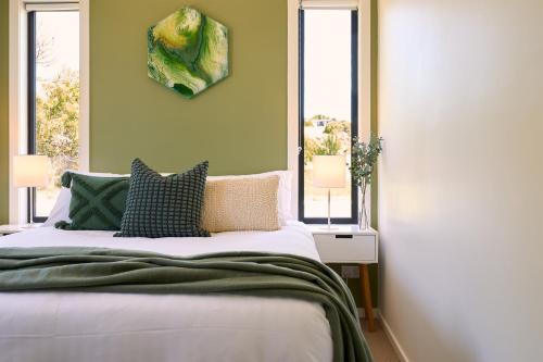 a bedroom with a large bed with two windows at Gumleaf in Coles Bay