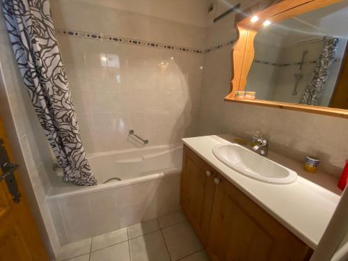 La salle de bains est pourvue d'un lavabo, d'une baignoire et d'un rideau de douche. dans l'établissement Appartement lumineux 58 m², 2 chambres, balcon, parking, La Chapelle-d'Abondance - FR-1-692-106, à La Chapelle-dʼAbondance