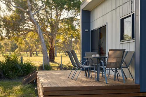 a deck with chairs and a table on a house at Gumleaf in Coles Bay