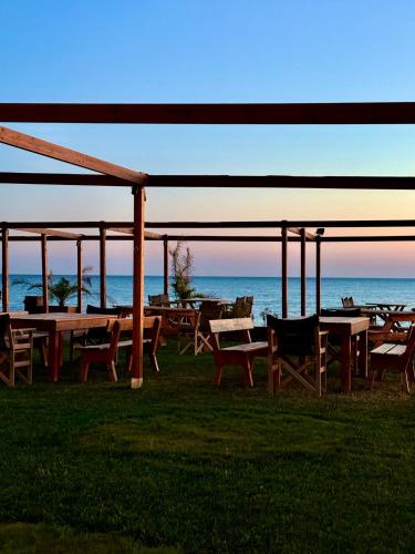 a group of tables and chairs with the ocean in the background at LUXE COASTAL RETREAT Apartment in Alexandroupoli