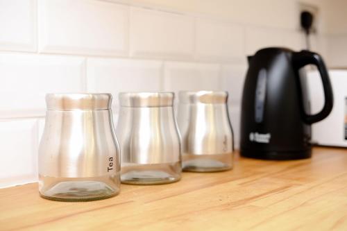 three glass bottles sitting on a kitchen counter at Grace Double Bedroom Manchester in Middleton