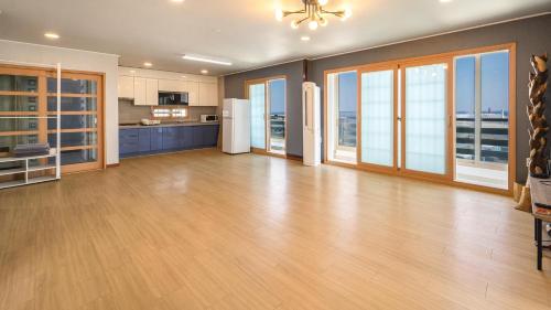 eine große Küche mit Hartholzboden und großen Fenstern in der Unterkunft Gangneung Basecamp Pension in Gangneung