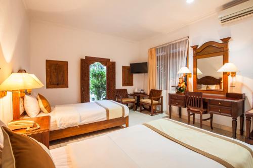 a hotel room with two beds and a desk at Beach Front Hotel Danau Tamblingan St Sanur Bali in Sanur