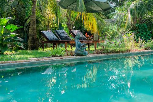 a pool with two chairs and a table next to the water at Villa Lanka Relax in Hikkaduwa