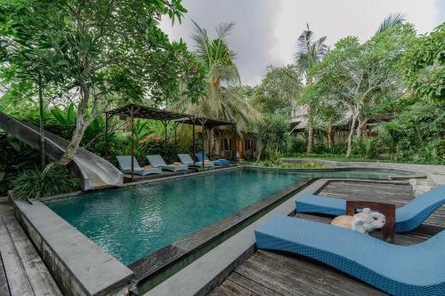 a pool with chairs and a slide in a resort at The Onion Collective in Ubud