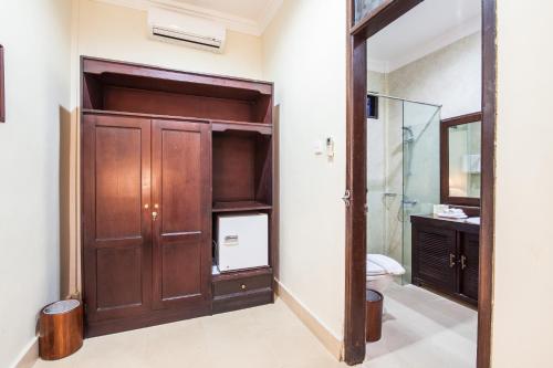 a bathroom with a wooden closet and a toilet at Beach Front Hotel Danau Tamblingan St Sanur Bali in Sanur