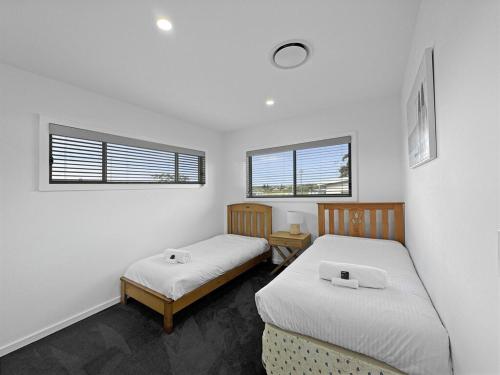 two beds in a room with two windows at Seaside Village Retreat in Shellharbour