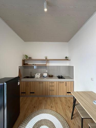 a kitchen with wooden cabinets and a black refrigerator at Sampai Living Tugu in Yogyakarta