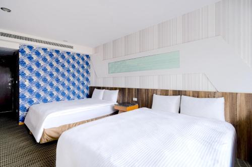 two beds in a hotel room with white sheets at Sunny Hotel in Taipei