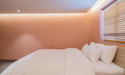 a bedroom with a white bed and a window at Jamsil Orosie Tourist Hotel in Seoul