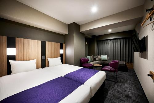 a hotel room with a large bed and a couch at hotel MONday Kyoto Karasuma Nijo in Kyoto