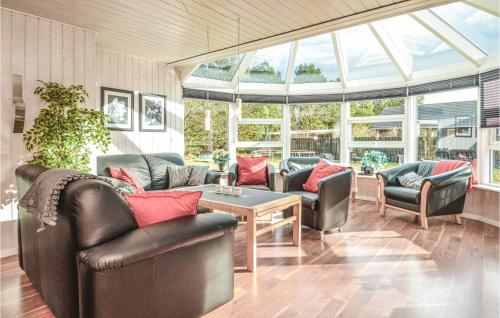 a living room with couches and a table and windows at Holiday Home Sønderballevej Blåvand Iii in Ho