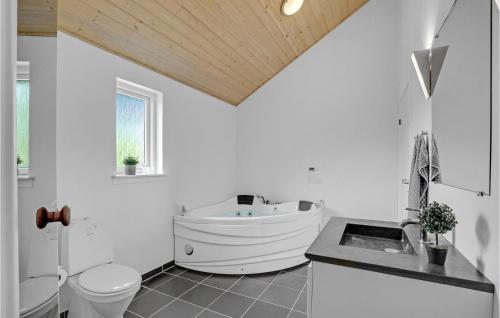 a bathroom with a tub and a toilet and a sink at Holiday Home Marthasvej in Trend