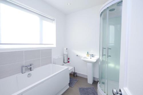 a white bathroom with a tub and a sink at Grace Double Bedroom Manchester in Middleton