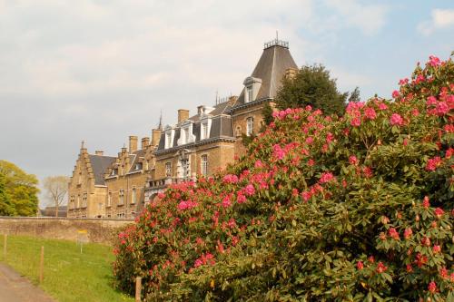 an old building with pink flowers in front of it at Domaine de Ronchinne - Château et Ecuries in Maillen