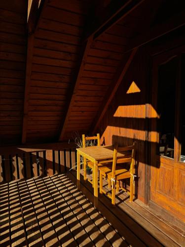 a wooden table and chairs on the porch of a cabin at domek w zaczarowanym lesie in Istebna
