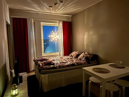 a bedroom with a bed and a window with a chandelier at Top Floor City Apartment in Rovaniemi