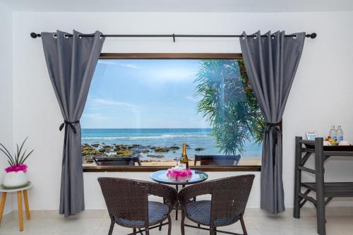 a table and chairs in front of a window with the ocean at Lanta Beachfront Resort in Ko Lanta