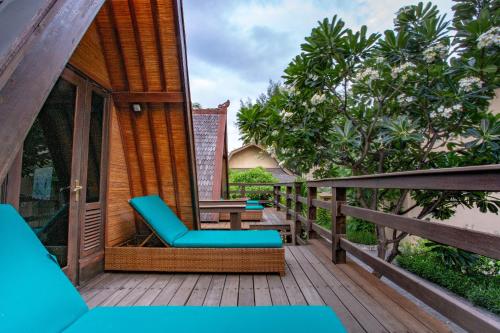 a wooden deck with blue chairs on a house at Vila Ombak in Gili Trawangan