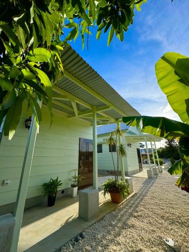 a white building with a pergola and plants at コラゾン Resort in Minamidaito