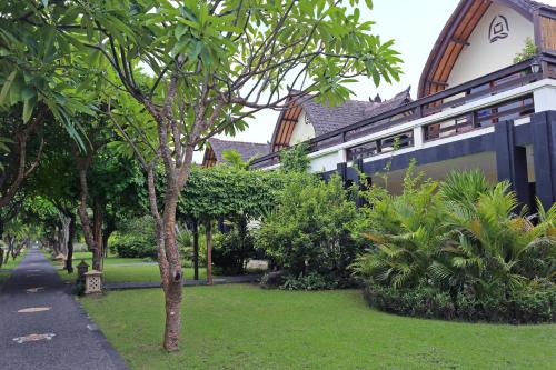 a building with trees and plants in a yard at Vila Ombak in Gili Trawangan