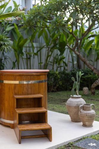 a wooden table with two vases sitting next to it at KALM Bali in Canggu