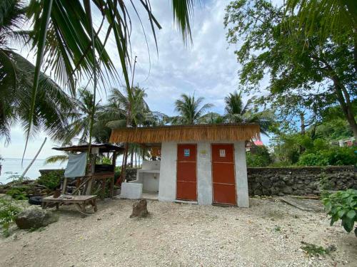 a small house with a red door on the beach at Alfonsa Tent Ground - Camp By The Sea in Oslob