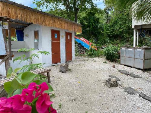 a house with red doors and pink flowers in front of it at Alfonsa Tent Ground - Camp By The Sea in Oslob