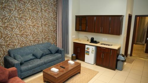 a living room with a blue couch and a kitchen at هذه ليلتي- اليرموك- طريق الدمام This Lailaty Al Yarmouk-Dammam Road in Riyadh