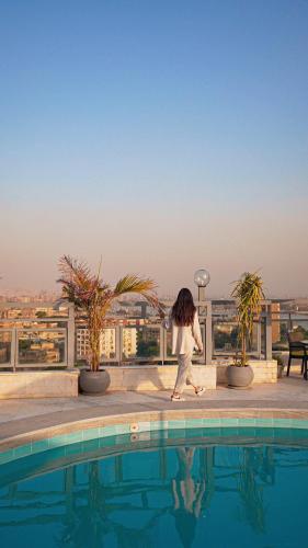 a woman walking next to a swimming pool at Maadi Hotel in Cairo