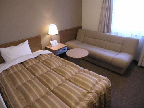 a hotel room with a bed and a couch at Ryugasaki Plaza Hotel Shinkan in Ryūgasaki