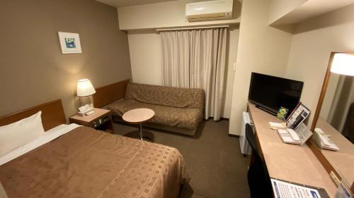 a hotel room with a bed and a couch at Ryugasaki Plaza Hotel Shinkan in Ryūgasaki