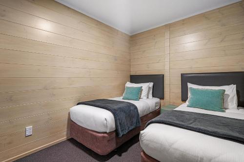 two beds in a room with wooden walls at Tasman Holiday Parks - Rotorua in Rotorua