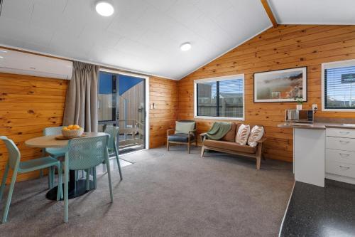 a living room with wooden walls and a table and chairs at Tasman Holiday Parks - Rotorua in Rotorua
