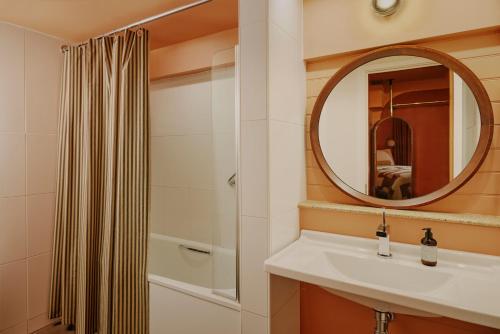Un baño con lavabo, espejo y ducha. en Ember Locke Kensington, en Londres