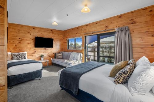 a bedroom with two beds and a tv and a couch at Tasman Holiday Parks - Rotorua in Rotorua
