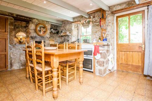 a large kitchen with a wooden table and chairs at White Rose Beach Cottage Sea-Views Garden in Sennen