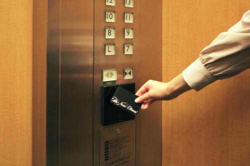 a hand is pushing a button on an elevator at Hotel New Otani Tokyo Garden Tower in Tokyo