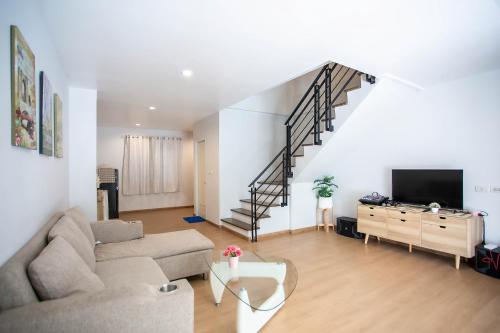 a living room with a couch and a staircase at Bangsean Smile Home บ้านสไมล์ บางแสน in Bangsaen